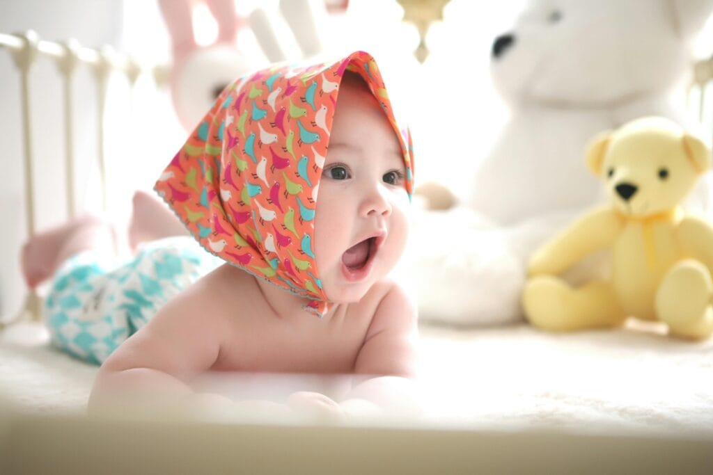 pexels-photo-265987-265987 Charming baby with colorful scarf surrounded by cute plush toys, highlighting innocence indoors.